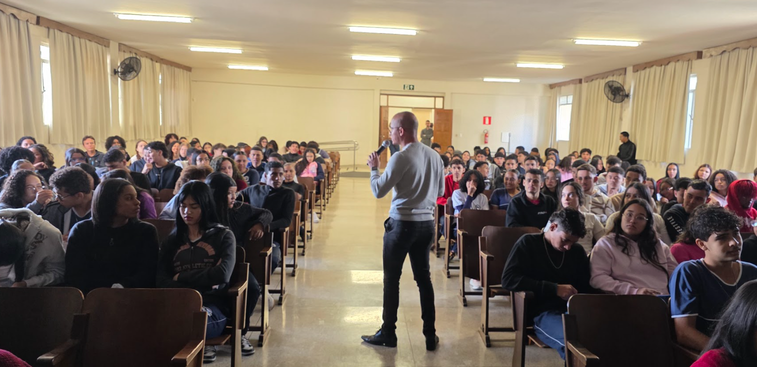 Amauri conversando com adolescentes em um auditório escolar